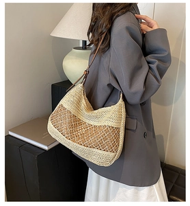 Detail of hollow woven straw tote bag featuring brown leather shoulder strap and texture