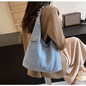 Détail du sac cabas en denim bleu clair avec broderie élégante de roses blanches
