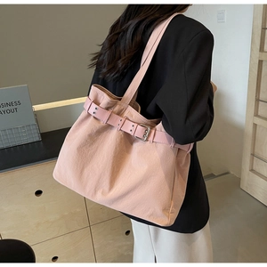 Detail view of pink tote bag showing textured fabric and silver metal buckle accent