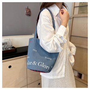 Détail du sac cabas en denim bleu avec imprimé lettres blanches et doublure à carreaux