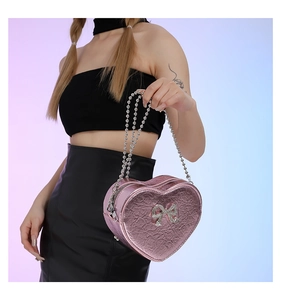 Detail of pink metallic heart bag with pleated texture and rhinestone bow decoration