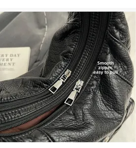 Detail of smooth double silver metal zippers on black textured PU leather bag