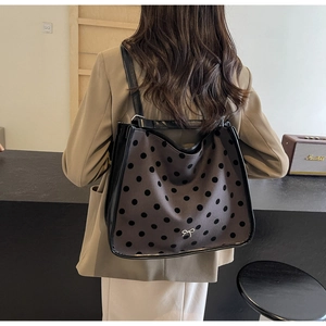 Detailed view of dark grey polka dot tote bag with silver bow charm and black trim
