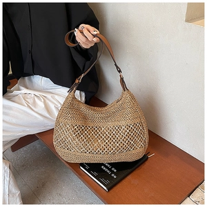 Detail of hand-woven straw beach bag featuring intricate mesh pattern and brown leather strap