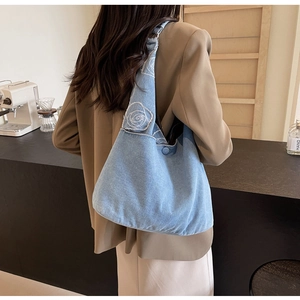 Détail du sac cabas en jean bleu clair avec broderie rose blanche sur modèle