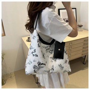 Détail d'un cabas blanc à motifs papillons noirs avec un mini porte-monnaie suspendu