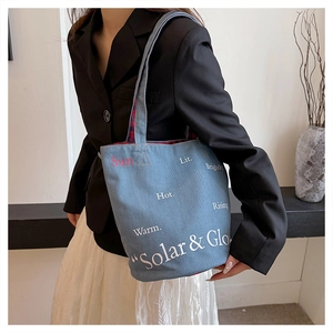 Détail du cabas en denim bleu avec imprimé lettres et doublure à carreaux rouges