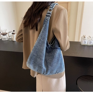 Detail of vintage washed denim hobo bag featuring wide strap and metallic ring design