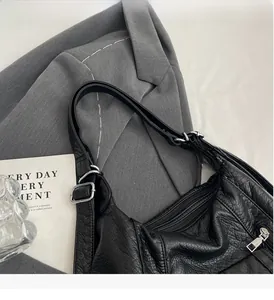 Close-up of black pebble grain PU leather bag with silver metal buckle and wide strap