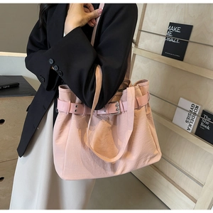 Detailed view of the pink nylon tote bag with leather buckle strap on a female model