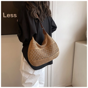 Detail of hand-woven straw beach bag with mesh cut-outs and brown leather strap