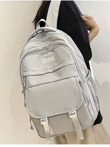 Vue détaillée d'un sac à dos gris en nylon avec lettrage fashion et poches zippées