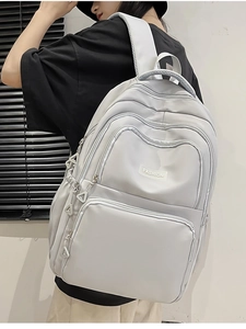 Detail view of a large grey nylon backpack with adjustable side buckles and multiple zip pockets