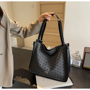 Detail of black striped tote bag with bow pattern and silver metal butterfly pendant