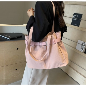 Detail of light pink waterproof tote bag with decorative buckle strap on a shoulder
