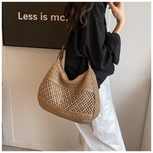 Detail of hand-woven straw hobo tote with hollow mesh pattern and leather shoulder strap