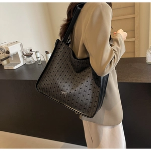 Detail of grey canvas tote bag with black bow jacquard and leather shoulder strap