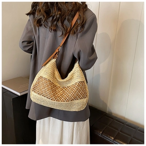 Close-up of handmade straw beach bag featuring large hollow mesh weaving and leather strap