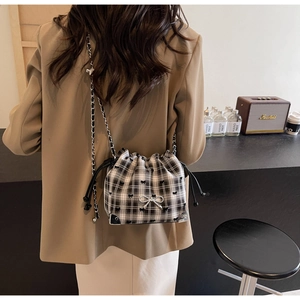 Detail of checkered canvas bucket bag with metal bow and protective corner guards