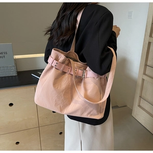 Detail view of pink fabric tote bag with decorative belt buckle worn on shoulder