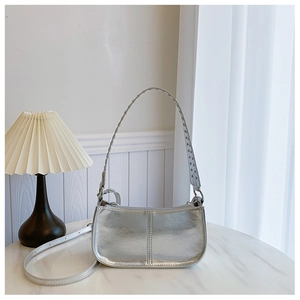 Détail du sac à main argenté métallisé avec clous posé sur une table en marbre