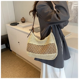 Detail view of woven straw shoulder bag with leather strap on a fashion model