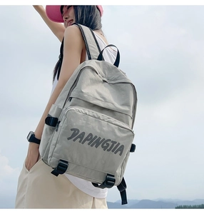Detail view of light gray nylon backpack with zip pocket and textured synthetic fabric
