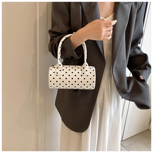 Chic white cylinder shoulder bag with black polka dots shown on a female model