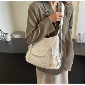 Detailed view of white soft PU leather shoulder bag with multiple pockets and wide strap