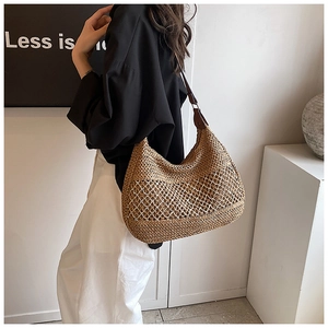 Detail of woven straw tote bag with mesh hollow design and dark brown leather strap