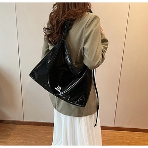 Detail of high-gloss black patent leather Hobo bag with white MA logo on a fashion model
