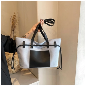 Detailansicht der grauen Canvas-Tasche mit schwarzen PU-Lederriemen und seitlichem Kordelzug
