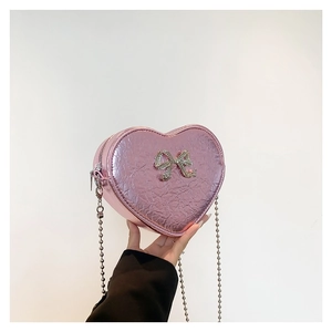 Pink heart-shaped crossbody bag with rhinestone bow and metallic pleated finish