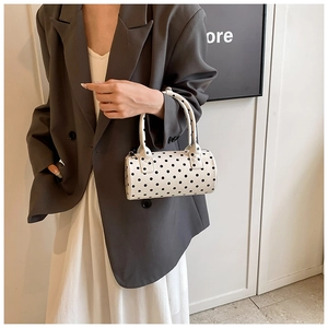 Detailed view of women's white PU leather cylinder bag with classic black polka dots