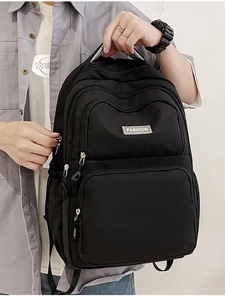 Detailed view of the black nylon backpack showing multiple zipper pockets and fabric texture