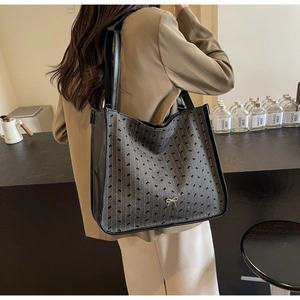 Detailed shoulder view of a large grey patterned tote bag with stylish black leather straps