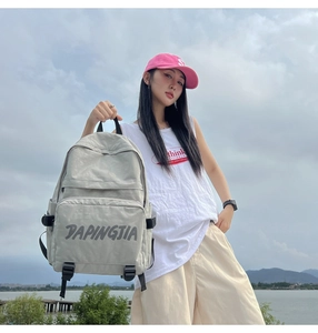 Outdoor shot showing side view of light grey nylon backpack with side pocket and buckle