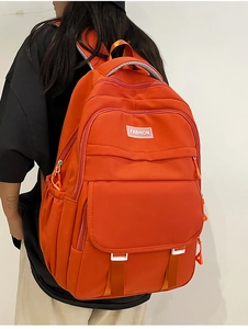 Détail d'un sac à dos en nylon orange vif avec fermetures éclair et poche latérale pour bouteille