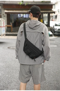 Detail of black nylon waist bag with multiple utility pockets shown in a street scene