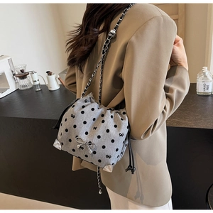 Detail of grey polka dot fabric bag with silver metal bow and reinforced metal corners