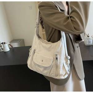 Detail of off-white PU leather shoulder bag featuring multi-zipper pockets and lychee texture