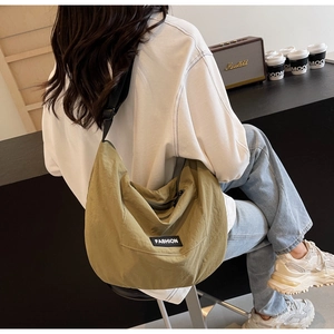 Detail view of the olive green nylon crescent bag with adjustable strap and fashion label