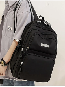 Detail view of black nylon backpack with multi-layer zippers and fashion label