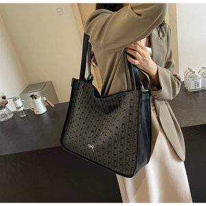 Detail of large grey jacquard tote bag with black bow embroidery and leather trim