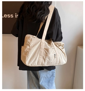 Detail view of a beige nylon tote bag featuring side pockets and VEILA brand logo