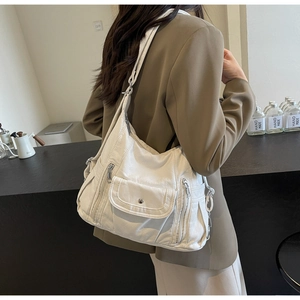 Close-up of white PU leather shoulder bag featuring metal zippers and litchi grain texture