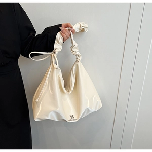 Close-up of creamy white faux leather handbag with pleated handle and metal logo