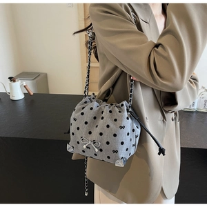 Detail of grey polka dot drawstring bag with silver bow ornament and metal corners