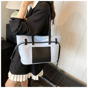 Hellblaue Canvas-Tragetasche mit schwarzer Ledertasche, von einem Modell getragen