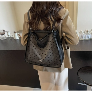 Rear view of a model wearing the dark grey fabric backpack with silver bow charm